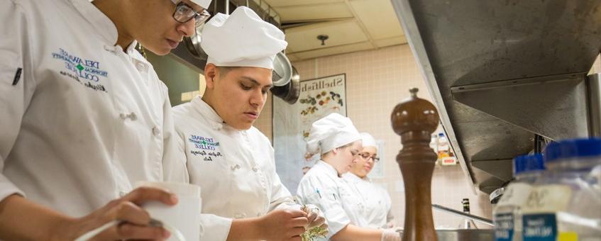 在斯坦顿校区，烹饪专业的学生穿着烹饪制服完成一项任务.